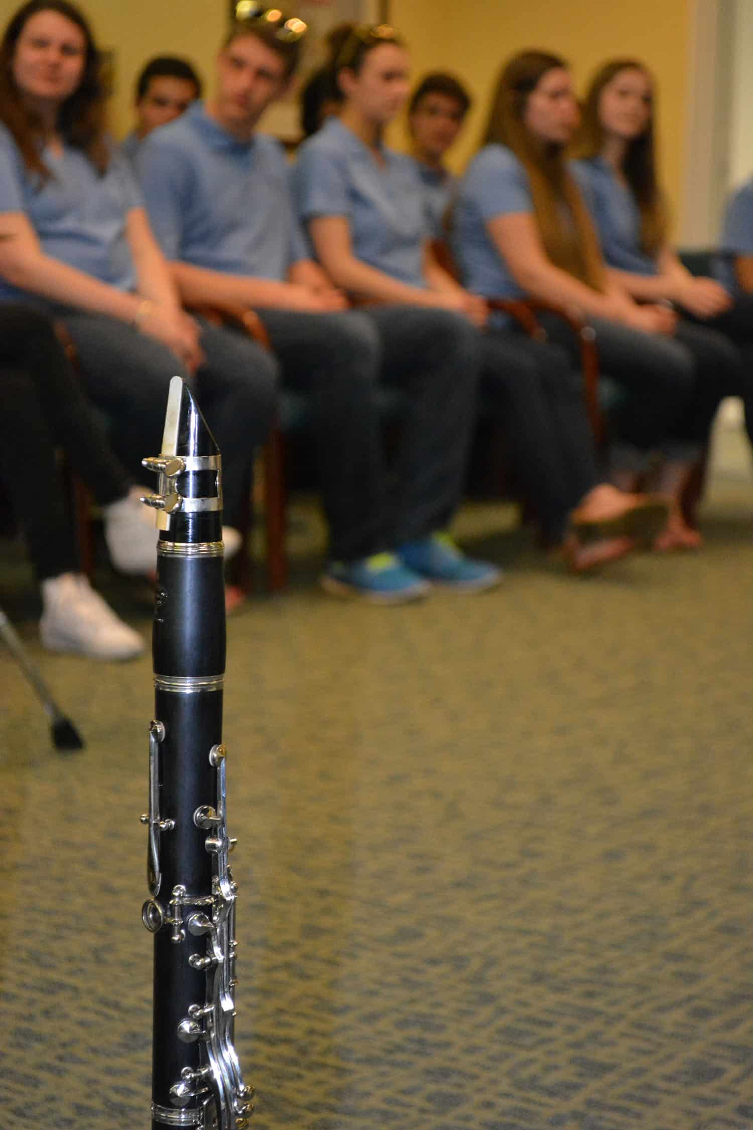 A clarinet stands in the foreground as Arts on Tour members sit behind it.
