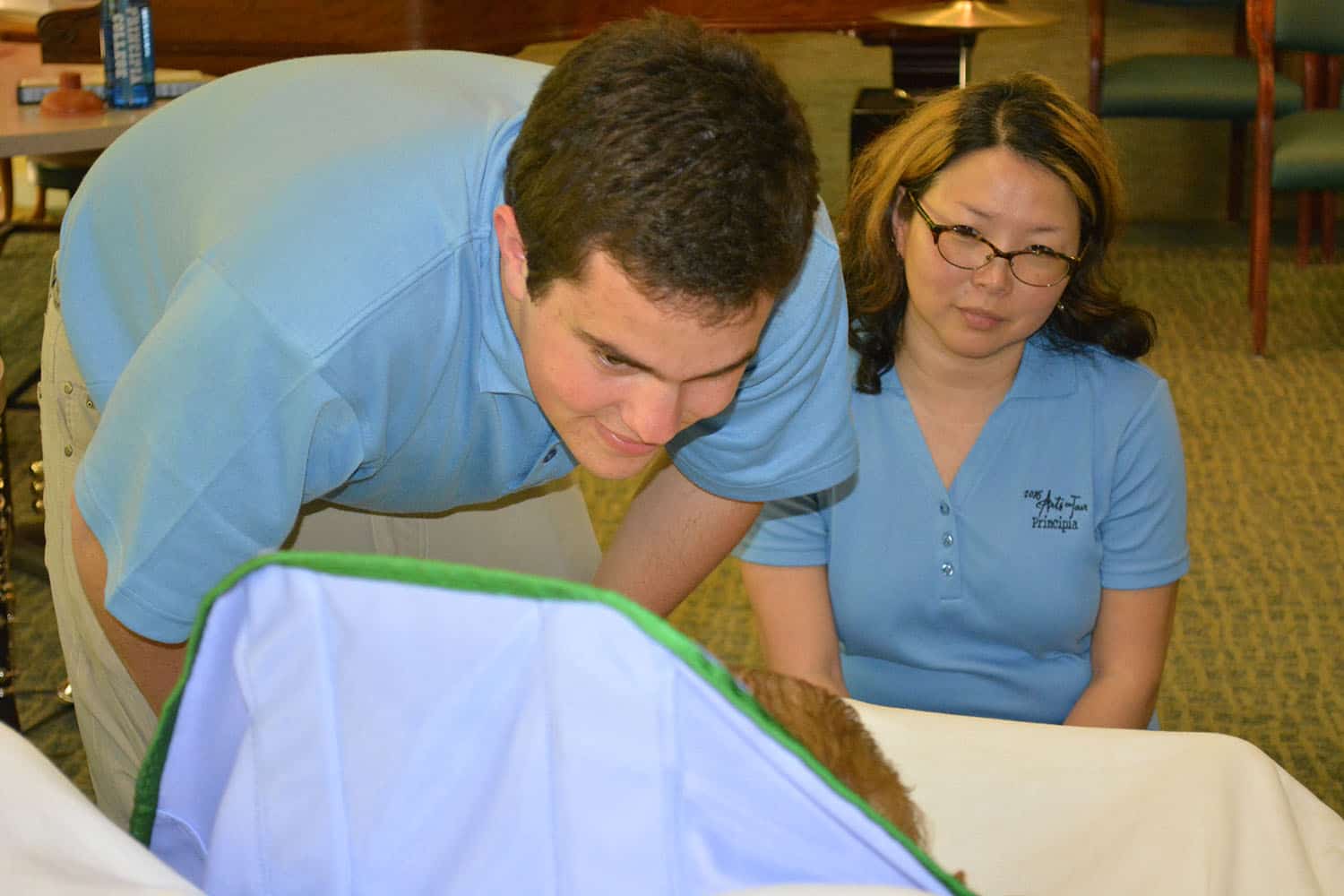 Two Arts on Tour members visit a Broadview guest resting in bed.