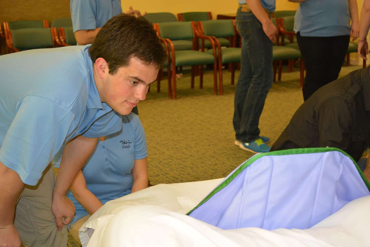 An Arts on Tour member leans in to greet a Broadview guest resting in bed.