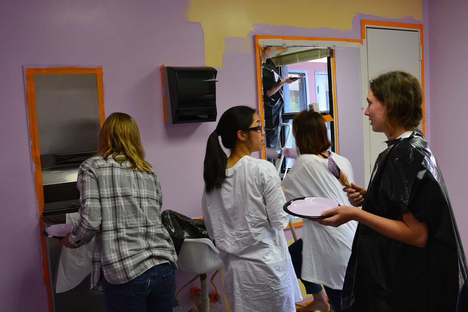 Four volunteers work together in the newly lavender-painted salon.