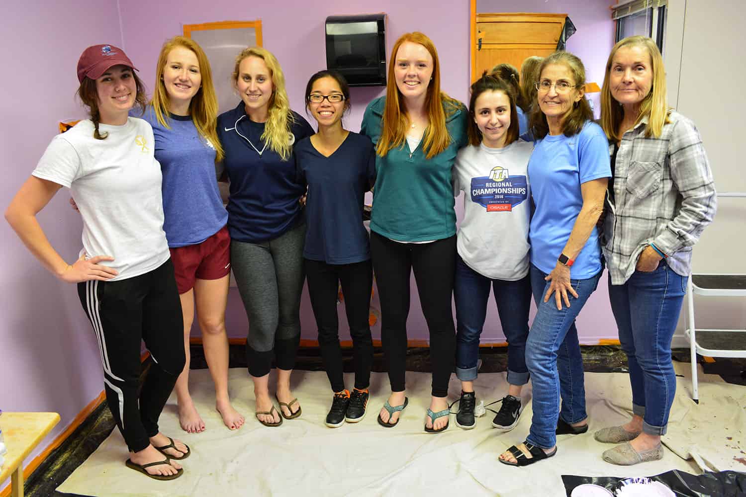 Eight volunteers pose together in the newly painted lavender salon.