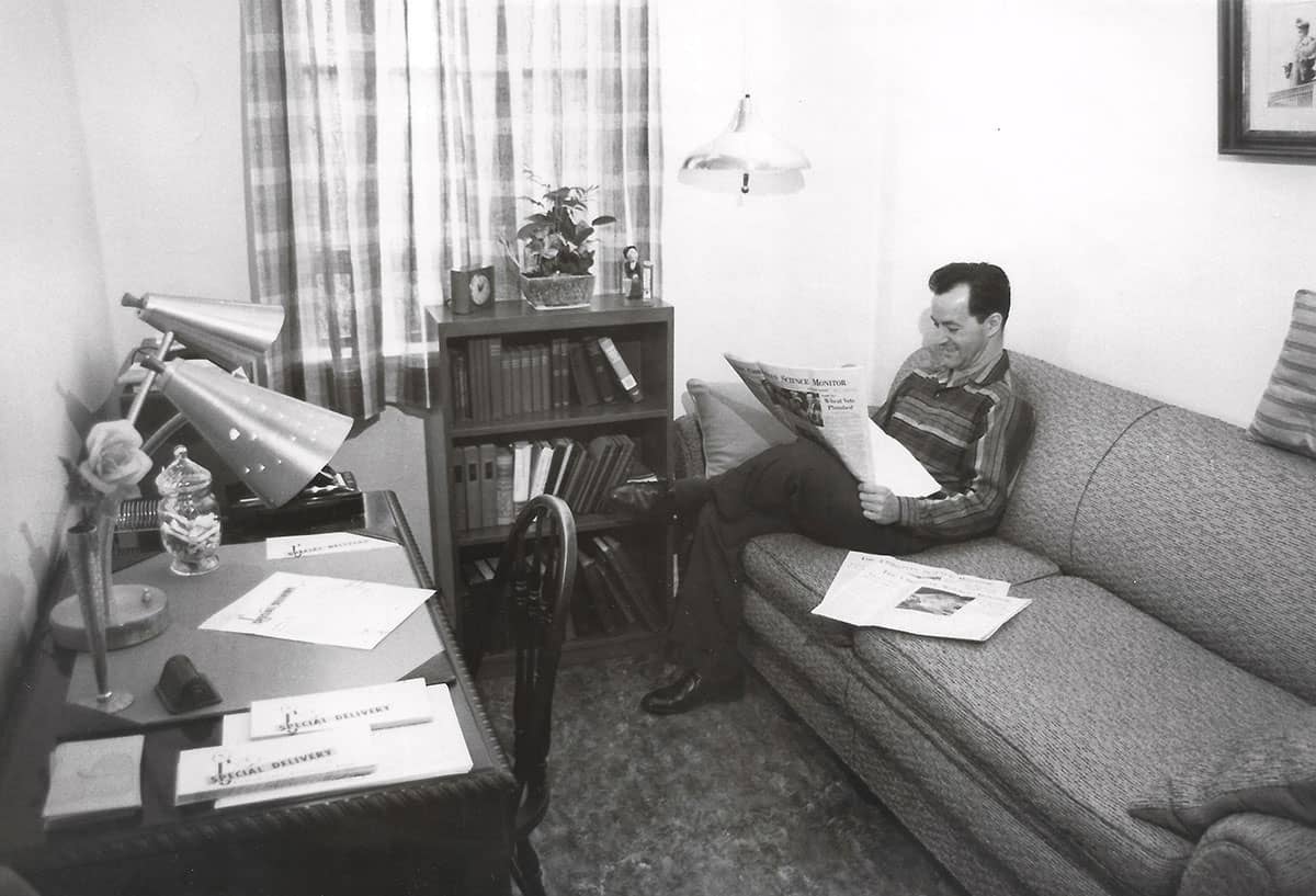 A man reads The Christian Science Monitor in a furnished waiting room.