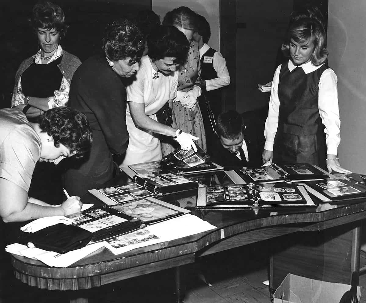 Visitors gather around tables of historical photo albums.